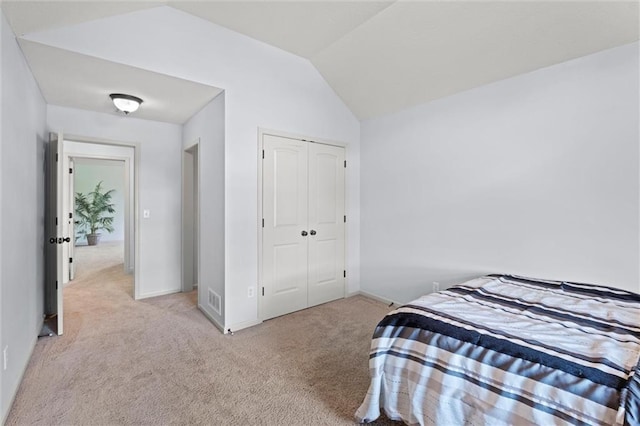 bedroom featuring carpet floors, vaulted ceiling, a closet, and baseboards