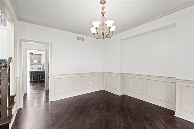 unfurnished dining area featuring a chandelier, ornamental molding, a wainscoted wall, and dark wood-style flooring