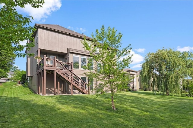back of property with stairway, a yard, and a deck