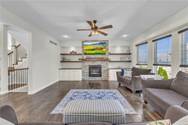 12765 N Imperial Dr, Platte City, MO 64079 - living room with dark wood-style flooring, a ceiling fan, a stone fireplace, baseboards, and stairway