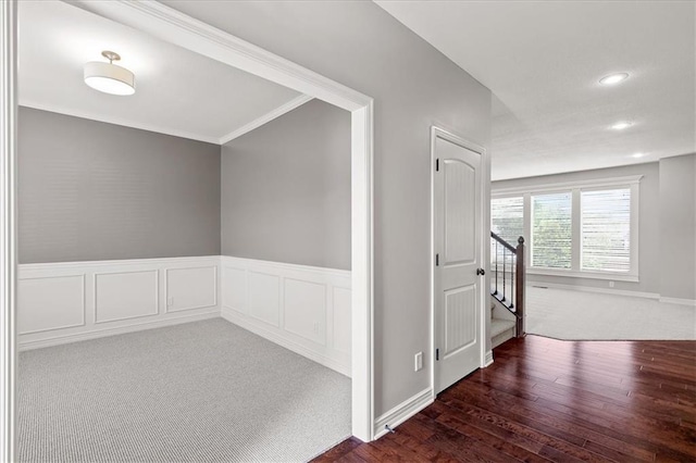 corridor with hardwood / wood-style floors, recessed lighting, stairs, a wainscoted wall, and crown molding