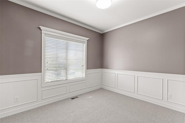 spare room featuring light carpet, wainscoting, and crown molding
