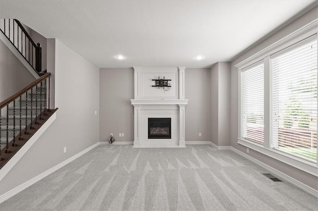 unfurnished living room featuring light colored carpet, baseboards, stairs, a fireplace, and recessed lighting