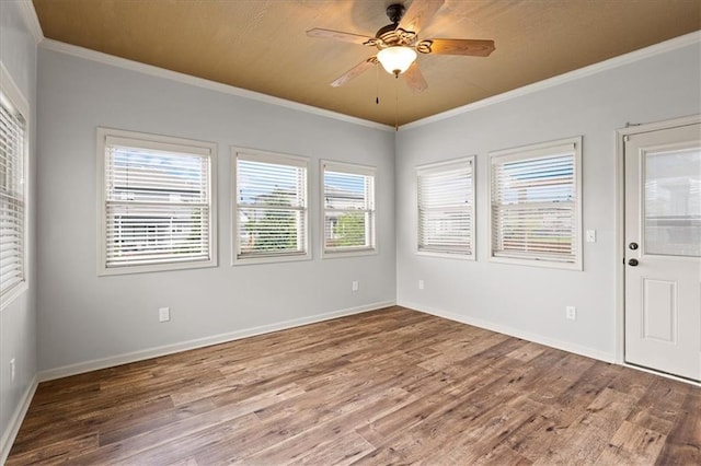 unfurnished room with wood finished floors, ornamental molding, a ceiling fan, and baseboards