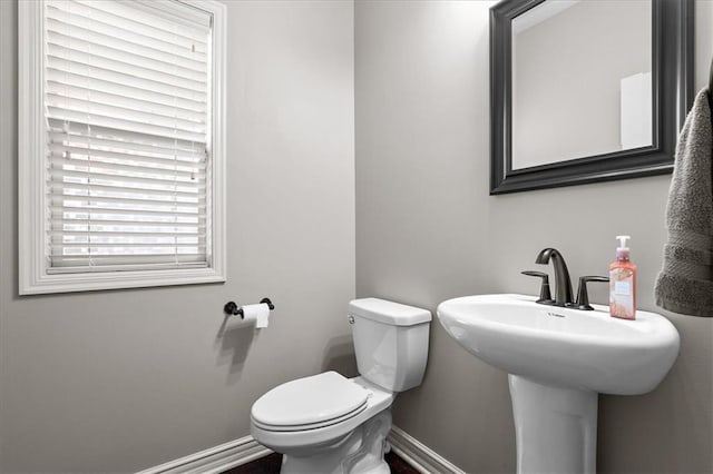 half bathroom with baseboards and toilet