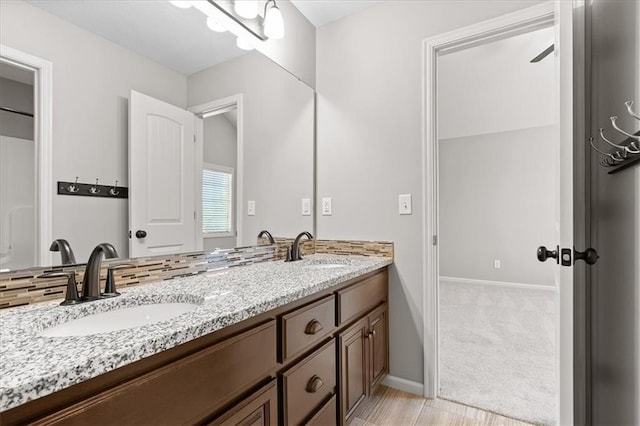 full bathroom featuring baseboards and double vanity
