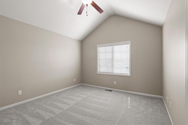 carpeted empty room with a ceiling fan, vaulted ceiling, and baseboards