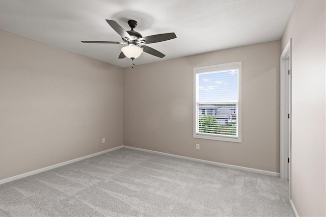 empty room featuring light carpet, a ceiling fan, and baseboards
