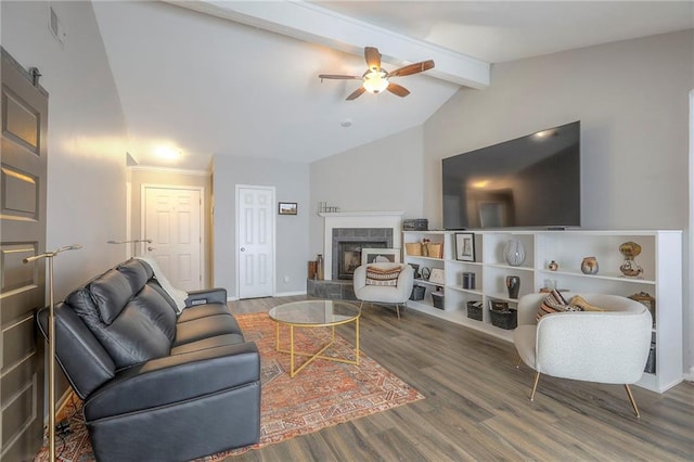living area featuring a tiled fireplace, visible vents, vaulted ceiling with beams, a ceiling fan, and wood finished floors