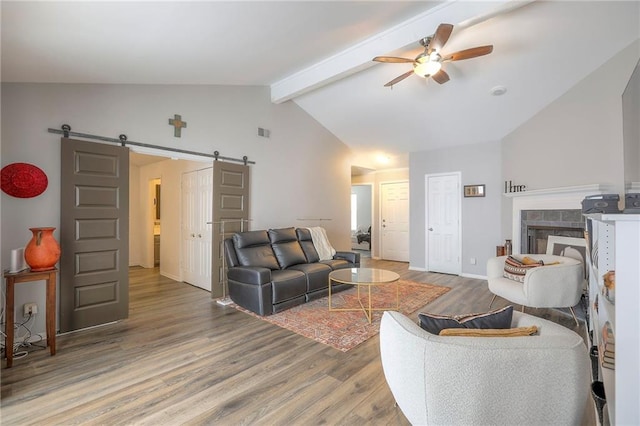 living area featuring a barn door, light wood-type flooring, visible vents, and ceiling fan