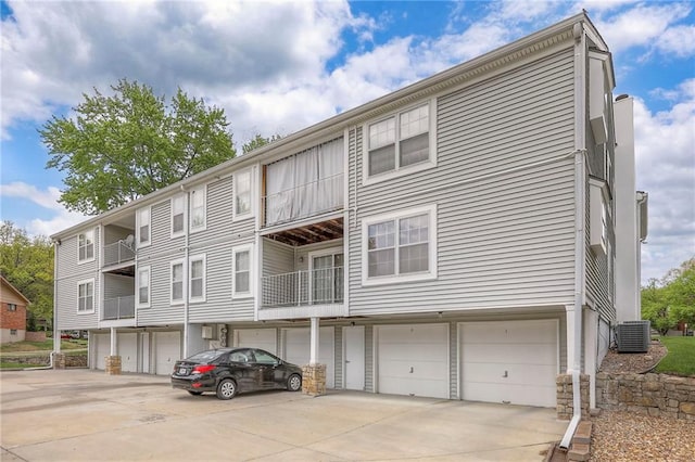 exterior space featuring an attached garage, driveway, and cooling unit
