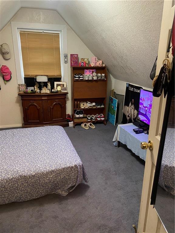 carpeted bedroom featuring a textured ceiling and vaulted ceiling