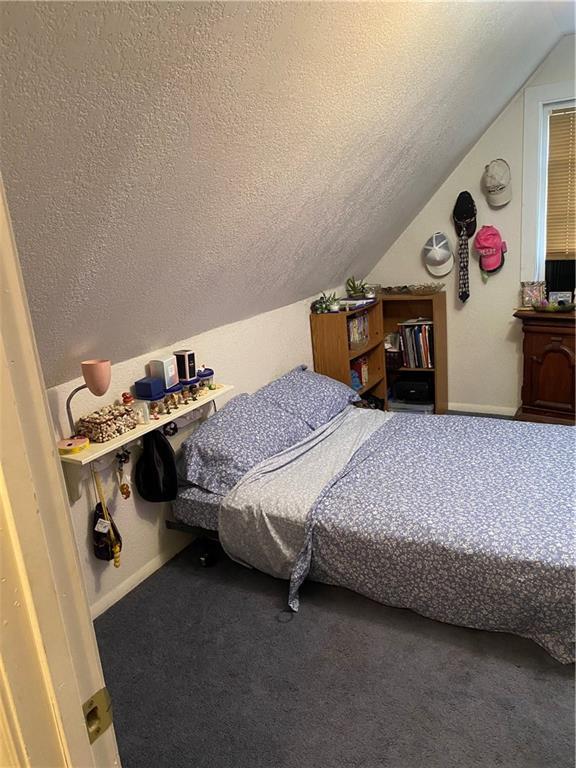 carpeted bedroom with a textured ceiling, lofted ceiling, and baseboards