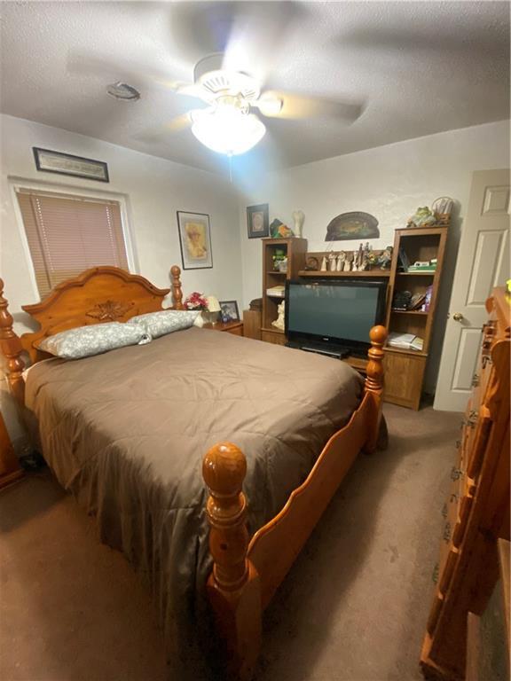 carpeted bedroom with a ceiling fan and a textured ceiling