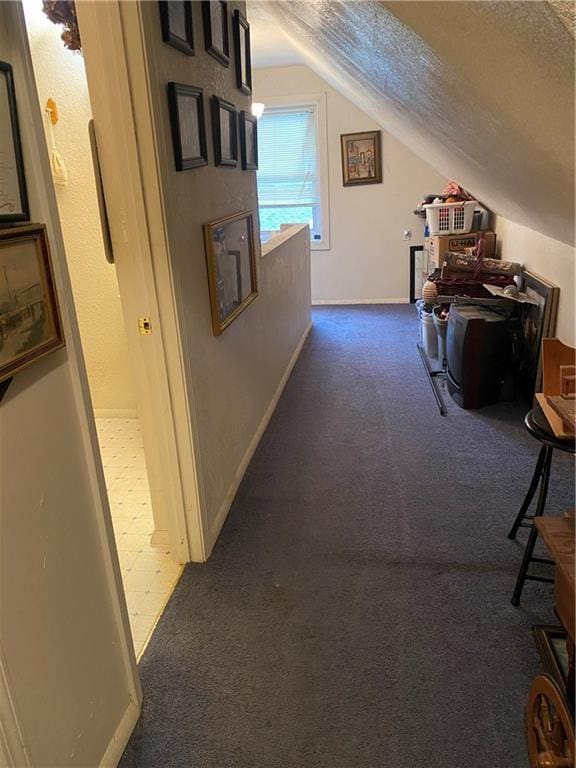 hall featuring baseboards, a textured ceiling, carpet, and lofted ceiling