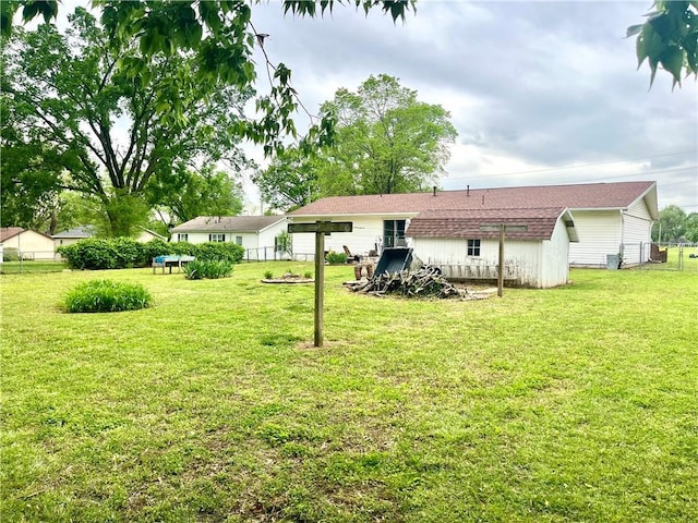 rear view of house with a yard, fence, an outdoor structure, and a storage unit