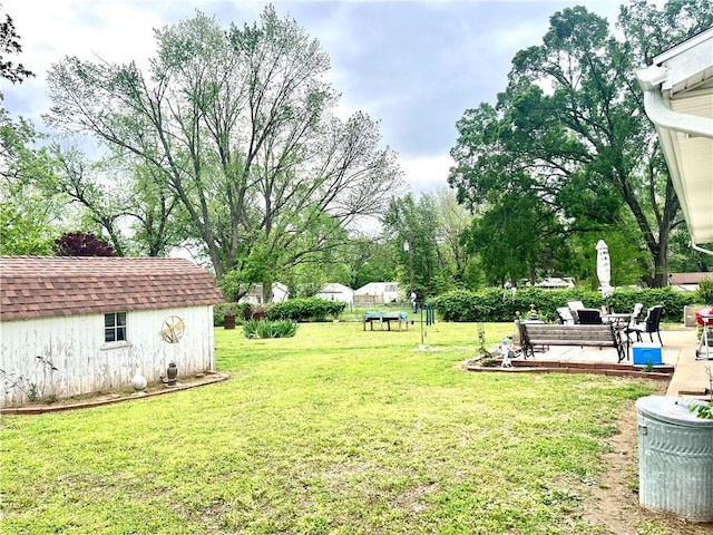 view of yard featuring a patio, a shed, and an outbuilding