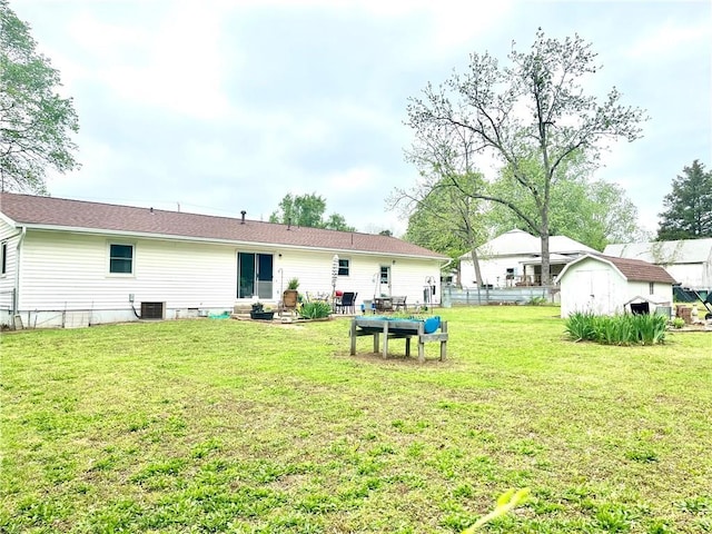 rear view of property with a yard, fence, an outdoor structure, and a storage unit