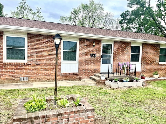 view of front of property with brick siding, a front lawn, and crawl space