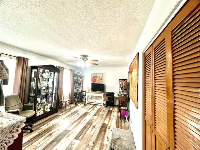 living room featuring a ceiling fan, a textured ceiling, and wood finished floors