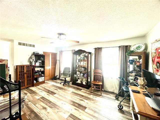 office area with visible vents, a ceiling fan, a textured ceiling, and wood finished floors