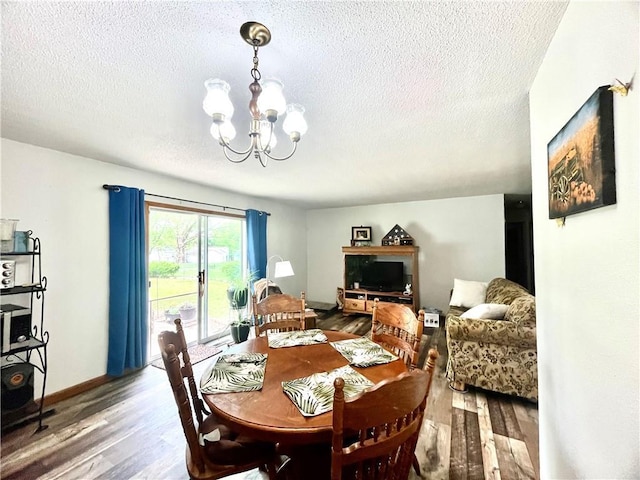dining area with a textured ceiling, wood finished floors, and a notable chandelier