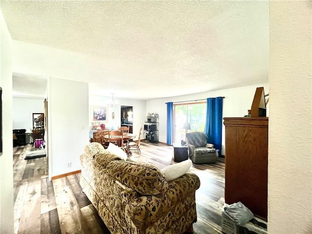 living area featuring a textured ceiling, a notable chandelier, and wood finished floors