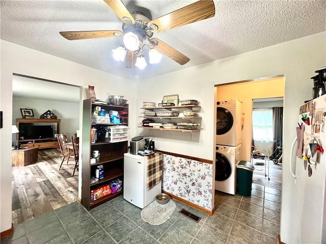 interior space with stacked washer and dryer, a textured ceiling, visible vents, and ceiling fan