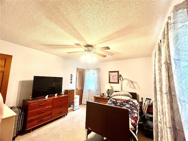 bedroom featuring ceiling fan, light carpet, and a textured ceiling