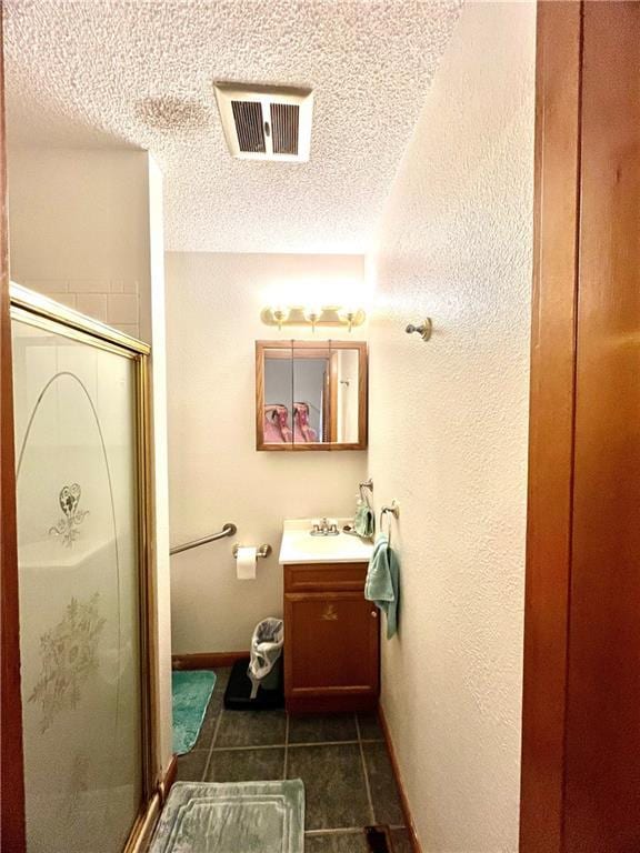 full bathroom featuring vanity, a textured ceiling, tile patterned floors, a shower stall, and visible vents