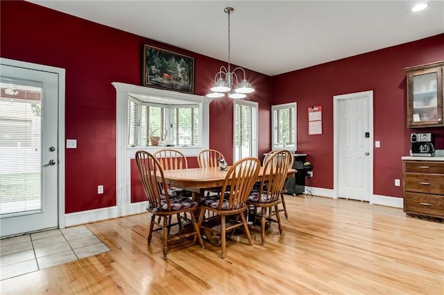 516 Parker St, Osawatomie, KS 66064 - dining space featuring light wood finished floors, an accent wall, baseboards, and a chandelier