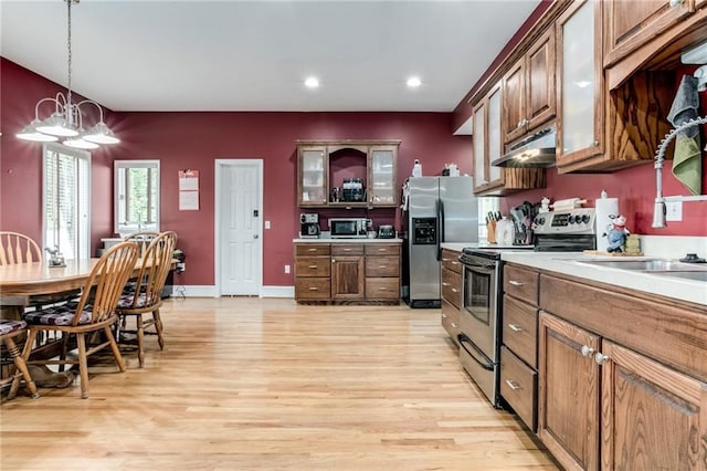 516 Parker St, Osawatomie, KS 66064 - kitchen featuring stainless steel appliances, under cabinet range hood, light wood-style flooring, light countertops, and glass insert cabinets