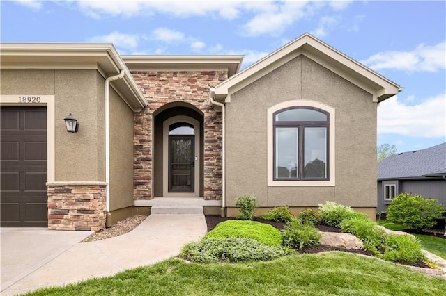 property entrance with stone siding, stucco siding, and a garage