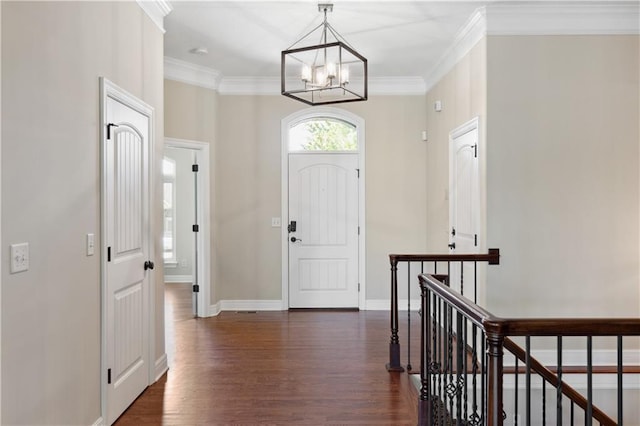 foyer entrance featuring dark wood-style flooring, a chandelier, crown molding, and baseboards