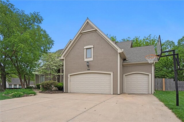 traditional-style home featuring roof with shingles, stucco siding, fence, and concrete driveway