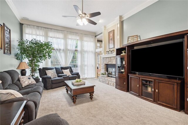 living area with a ceiling fan, ornamental molding, carpet, and a fireplace