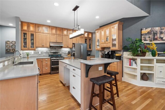 kitchen with backsplash, appliances with stainless steel finishes, a breakfast bar, and a sink