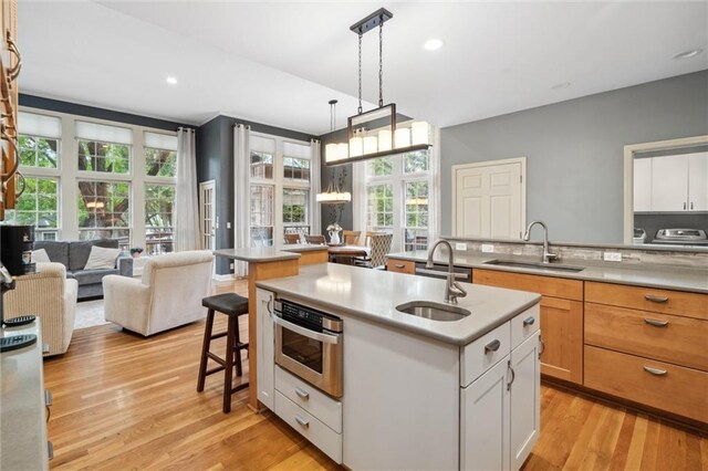kitchen with a sink, a breakfast bar area, light wood finished floors, and an island with sink