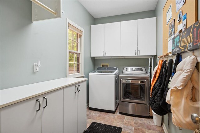 laundry room with washer and clothes dryer, cabinet space, and stone finish floor