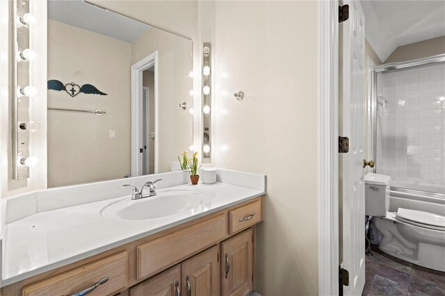bathroom featuring vanity, combined bath / shower with glass door, and toilet
