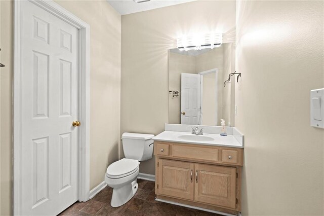 bathroom featuring baseboards, vanity, and toilet