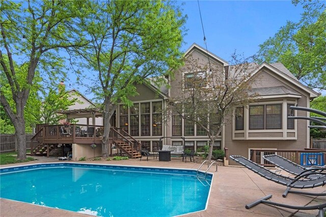 view of swimming pool featuring a wooden deck, a sunroom, fence, a fenced in pool, and stairs