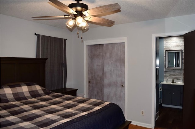bedroom featuring wood finished floors, a textured ceiling, connected bathroom, and a closet