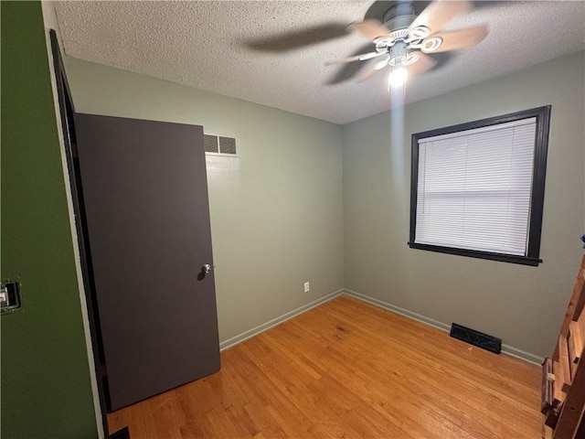 unfurnished bedroom featuring a textured ceiling, visible vents, light wood finished floors, and baseboards