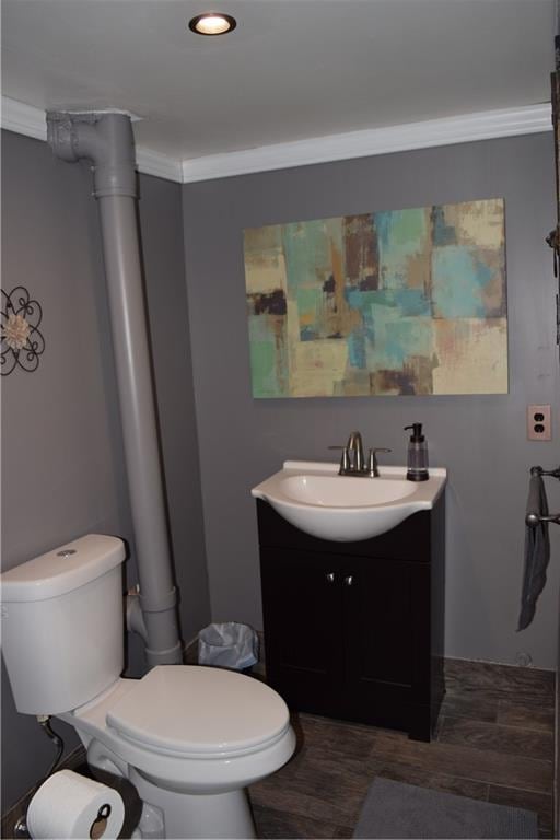 bathroom featuring wood finished floors, toilet, ornamental molding, and vanity