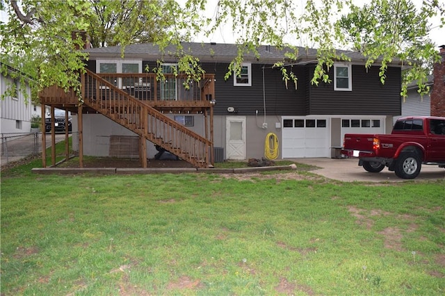 back of property featuring a deck, fence, a garage, a lawn, and stairs