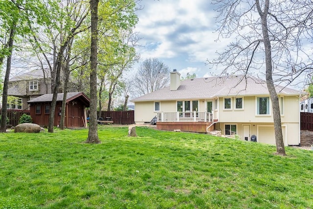 rear view of house with a wooden deck, fence, a chimney, and a garage