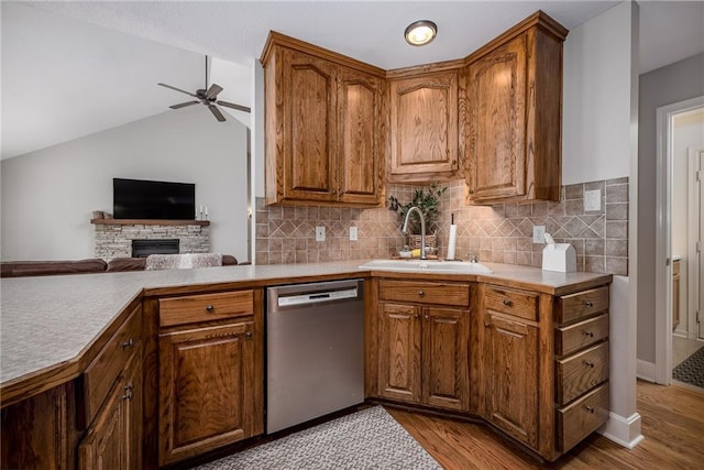 kitchen with ceiling fan, a sink, a fireplace, light countertops, and dishwasher