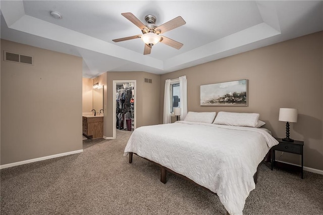 bedroom featuring baseboards, a tray ceiling, carpet floors, and visible vents