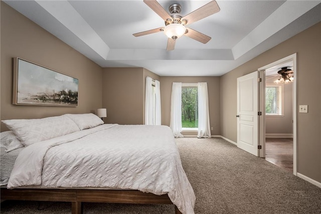 carpeted bedroom with baseboards, a ceiling fan, and a tray ceiling